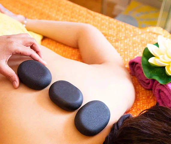Hot Stone Massage mit warmen Basaltsteinen auf dem Rücken